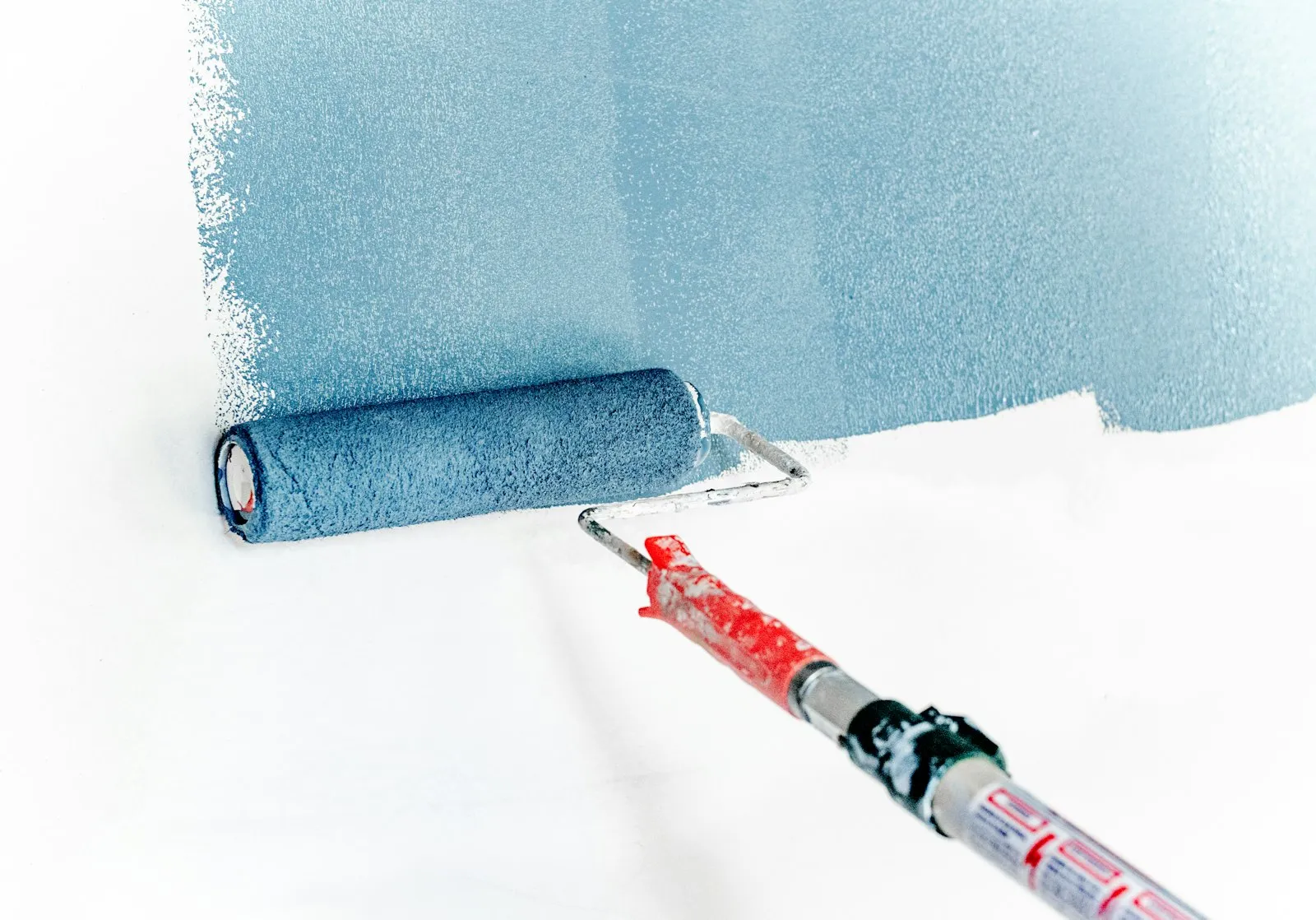 Farbrolle mit frischer blauer Wandfarbe bei Malerarbeiten